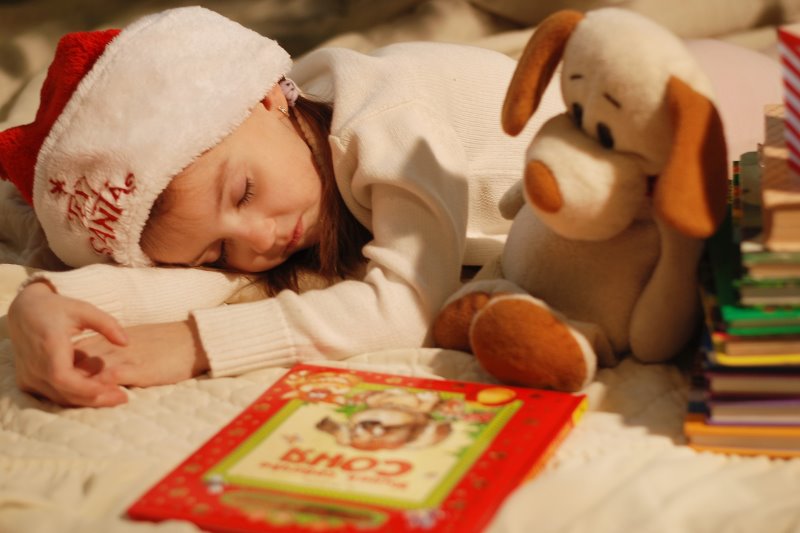 Mädchen schläft vor Weihnachtsbuch